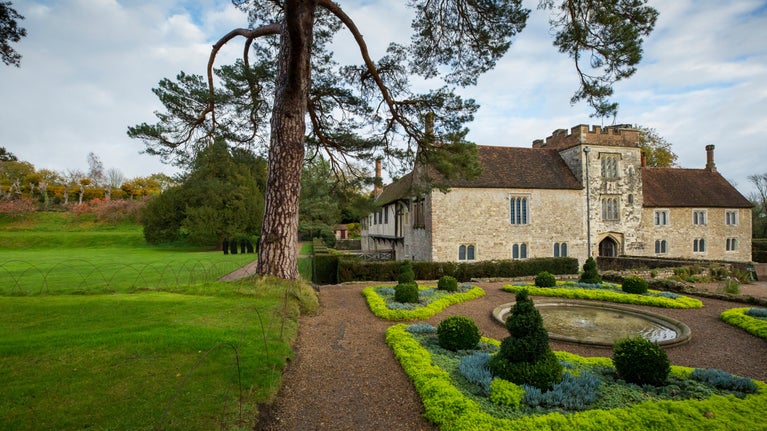 The west front of Ightham Mote as seen over a landscaped garden